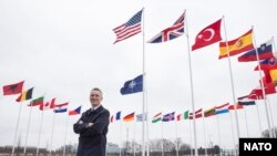 Jens Stoltenber, generalni sekretar NATO-a ispred zastave Severno-atlantskog saveza i zastava 29 clanica najvećeg odbrambenog saveza na svetu