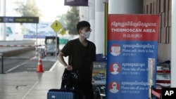 In this file photo taken on Friday, April 3, 2020, a tourist wearing a face mask enters an area of thermo scan at the quiet Phnom Penh International Airport in Phnom Penh, Cambodia.