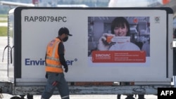 Seorang pekerja di samping kontainer bermuatan vaksin Covid-19, CoronaVac, yang baru didatangkan dari China, di China di Bandara Internasional Guarulhos, Sao Paulo, Brazil, Jumat, 18 Desember 2020.