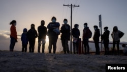 Migranti čekaju transport nakon što su iz Meksika ušli u SAD.