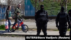 Montenegro, Podgorica, People pass behind a police checkpoint after the government tightened up measures for coronavirus 