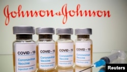 FILE - Vials with a sticker reading, "COVID-19 / Coronavirus vaccine / Injection only" and a medical syringe are seen in front of a displayed Johnson & Johnson logo in this illustration taken Oct. 31, 2020.