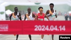 Chinese runner He Jie, second from right, Ethiopian Dejene Hailu Bikila and Kenyans Robert Keter and Willy Mnangat take part in a half-marathon in Beijing, China, April 14, 2024. (cnsphoto via REUTERS) 
