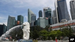 在新加坡滨海湾地区，人们在鱼尾狮雕像前拍照留念，与金融天际线相映成趣。(资料照片，2020年6月30日）