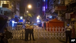 Police officers wearing masks stand guard at the closed area in Jordan district, in Hong Kong, Jan. 24, 2021. Thousands of Hong Kongers were locked down Saturday in an unprecedented move to contain a worsening coronavirus outbreak in the city.