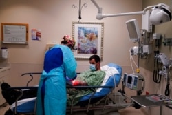 FILE - Registered nurse Jana Kendall tends to a COVID-19 patient in an emergency room at Mission Hospital in Mission Viejo, Calif., Dec. 21, 2020.