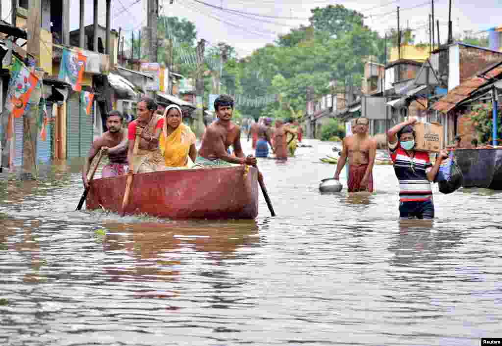 People wade through a flooded street to collect food and drinking water from a distribution center in Amta town of Howrah district in the eastern state of West Bengal, India.