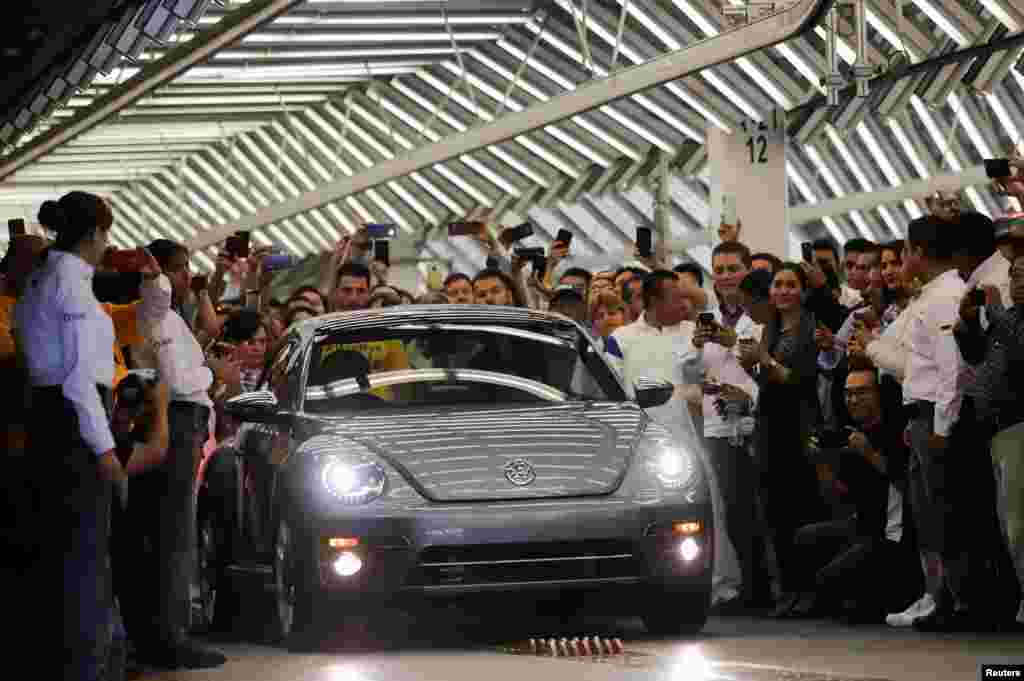 Employees take pictures of a Volkswagen Beetle car during a ceremony marking the end of production of VW Beetle cars, at company's assembly plant in Puebla, Mexico, July 10, 2019. The last Beetle is not for sale, but destined instead for a museum.