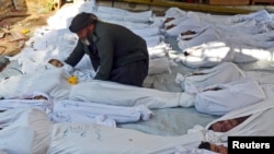 21일 시리아 다마스쿠스 외곽 고우타에서 정부군의 화학무기 공격으로 수백명이 사망했다는 주장이 나온 가운데, 한 남성이 사망한 아이의 시신을 살피고 있다.