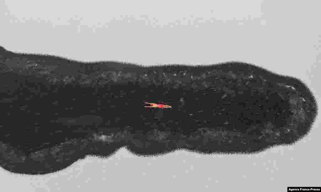 A winter swimming enthusiast swims in a partly frozen lake during snowfall at a park in Shenyang, in northeastern China's Liaoning province.