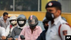Motorcyclists cover their faces with scarves to save themselves from air pollution as they wait at a crossing in New Delhi, India, Nov. 4, 2019. 
