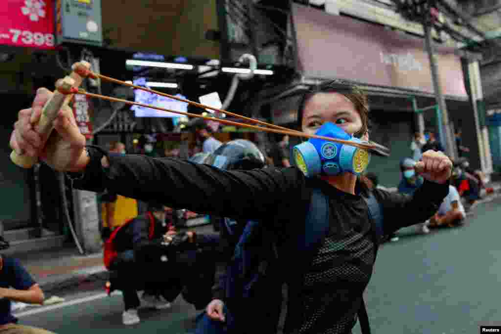 A demonstrator uses a slingshot during clashes with police at a protest against what they call the government's failure in handling the COVID-19 outbreak, in Bangkok, Thailand, Aug. 7, 2021.