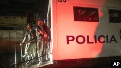 National Guard soldiers stand guard outside a police van holding people detained for not complying with COVID-19 regulations by breaking curfew and, or attending block parties, in the Petare neighborhood of Caracas, Venezuela, Aug. 7, 2020.
