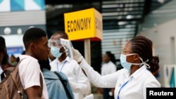 FILE PHOTO: A health worker checks the temperature of a traveller as part of the coronavirus screening procedure at the Kotoka International Airport in Accra, Ghana January 30, 2020. REUTERS/Francis Kokoroko/File Photo